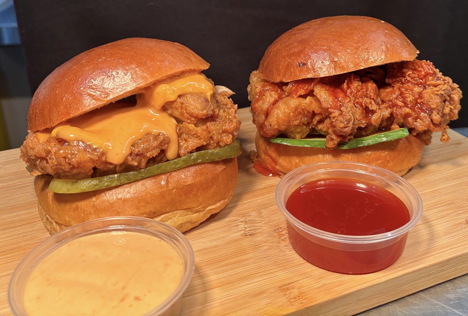 Two crispy chicken burgers with pickles and dips